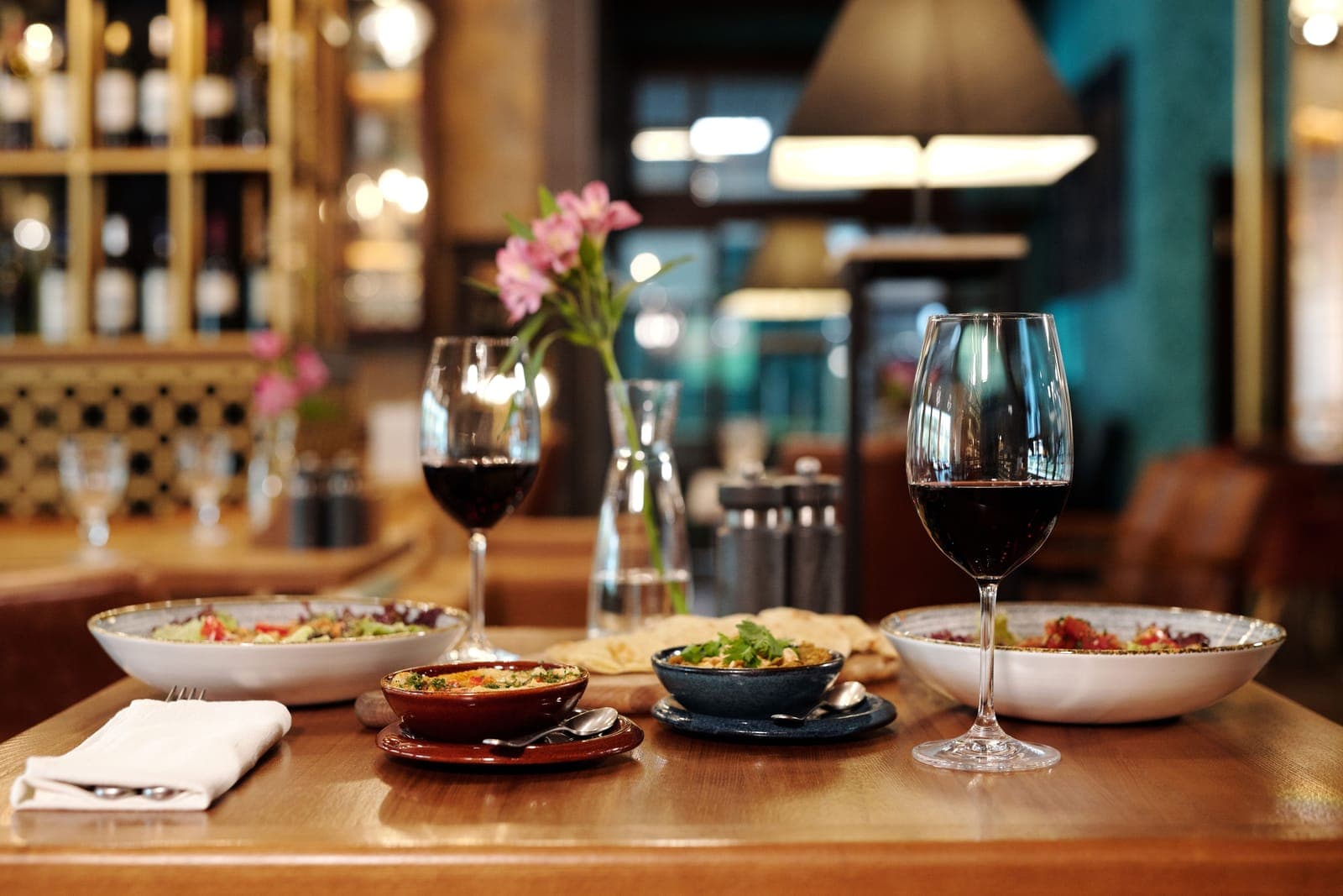 Two glasses of red wine and shared plates on a restaurant table