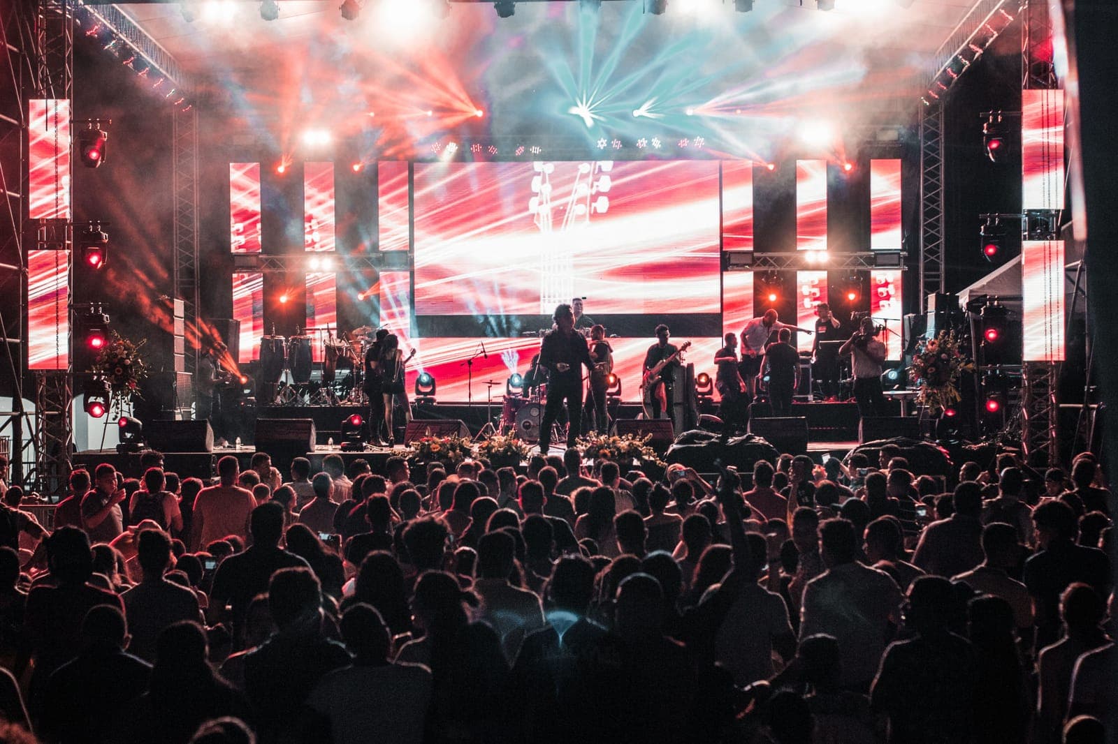 A band playing on a brightly lit outdoor stage in front of a large crowd